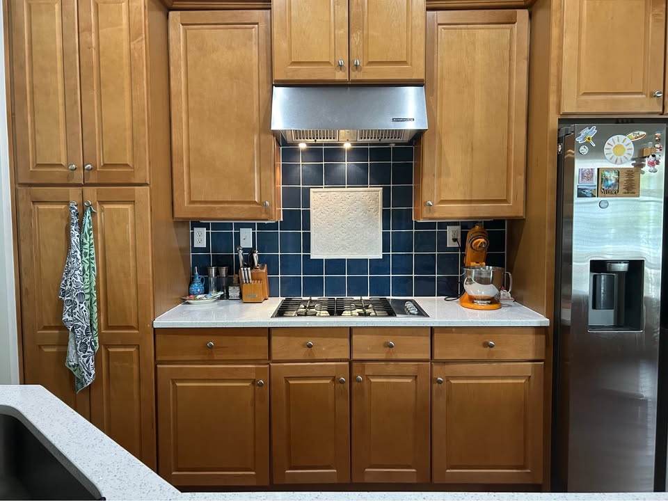 Kitchen with wood cabinets and navy blue tile backsplash