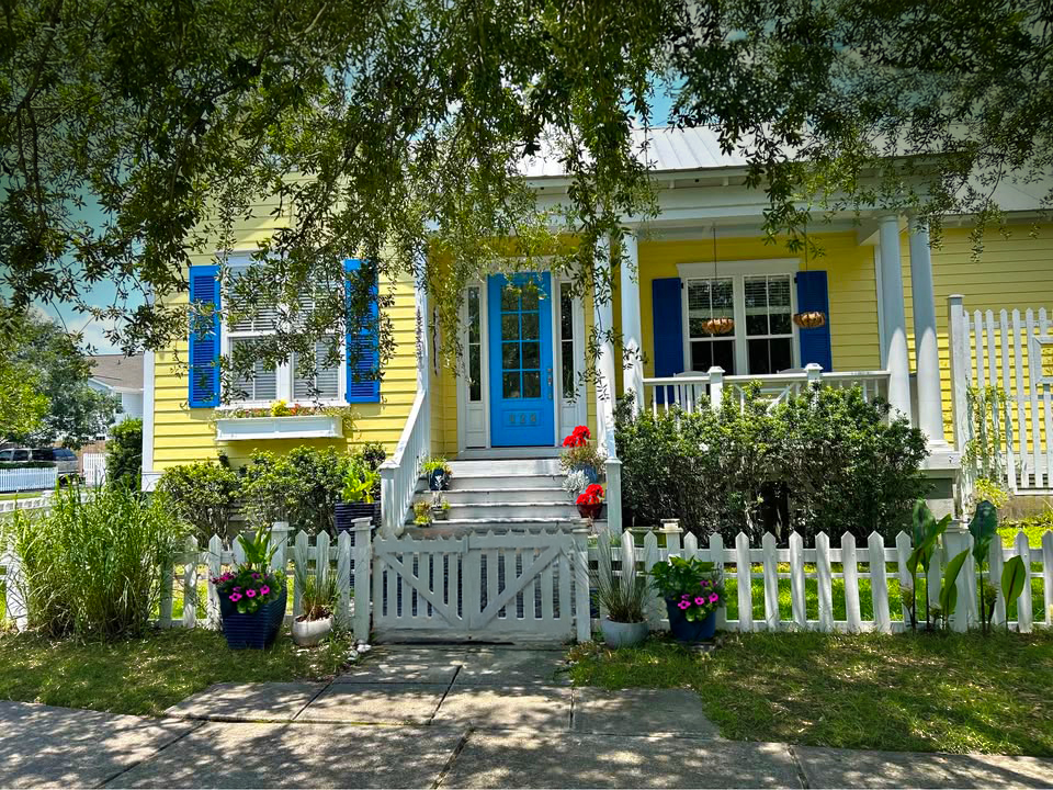 Yellow cottage-style home with navy shutters and covered porch